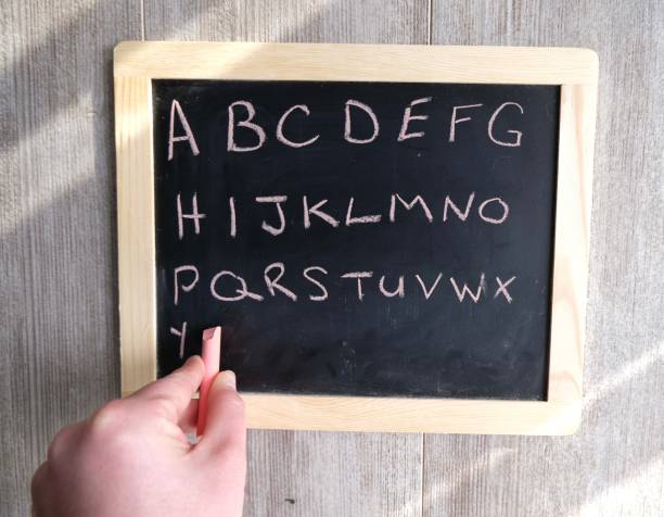 istock Hand writing alphabet on chalk board. Black chalk board with pink chalk. 1297718230