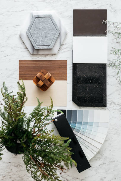 istock Top view of Material Selections including Granite tile, Marble tile, Acoustic tile, Walnut and Ash Wood Laminate and Painted color swatch with plant and flowers on marble top table. 1297719873