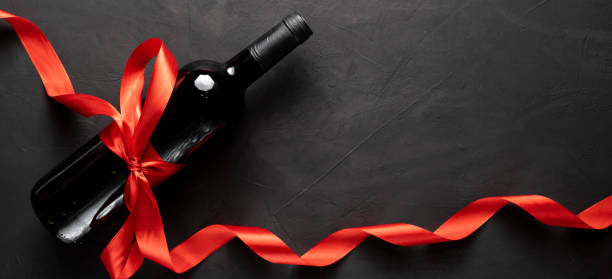istock Wine bottle with a red satin ribbon bow. Valentine's Day. On a concrete background. 1297721406