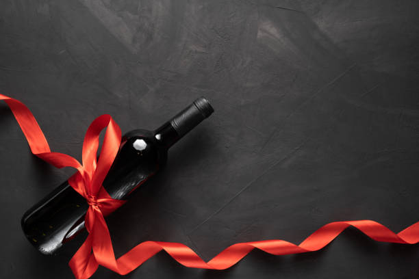 istock Wine bottle with a red satin ribbon bow. Valentine's Day. On a concrete background. 1297721409