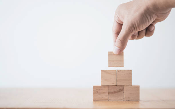 istock Hand putting and stacking blank wooden cubes on table with copy space for input wording and infographic icon. 1297721601