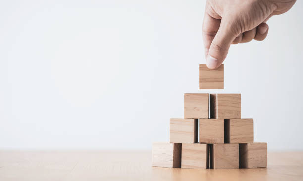 istock Hand putting and stacking blank wooden cubes on table with copy space for input wording and infographic icon. 1297722593