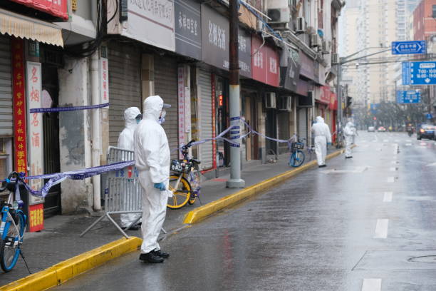 medizinisches personal im weißen hazmat-anzug auf der straße - shanghai stock-fotos und bilder