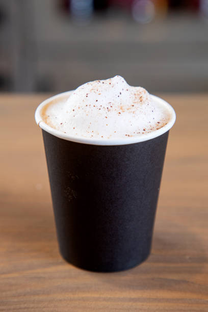 cappuccino con espuma y canela en taza negra desechable en el mostrador de la barra - latté cafe macchiato cappuccino cocoa fotografías e imágenes de stock