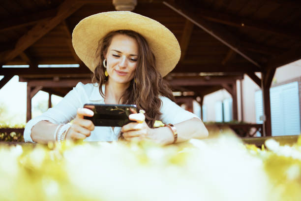 istock smiling trendy woman in shirt sending text message using phone 1297733625