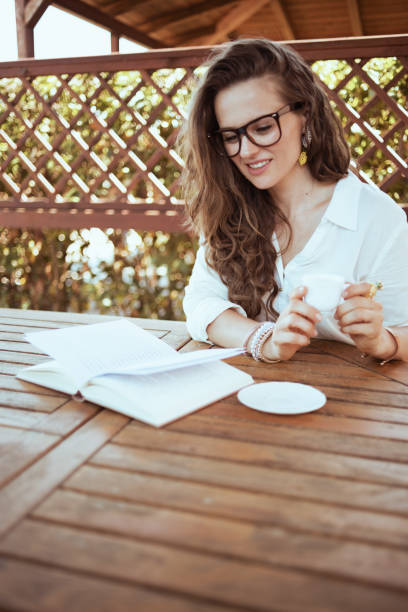 istock relaxed female sitting at table drinking coffee and reading 1297735090
