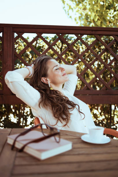 istock relaxed elegant woman in white shirt sitting at table 1297736446