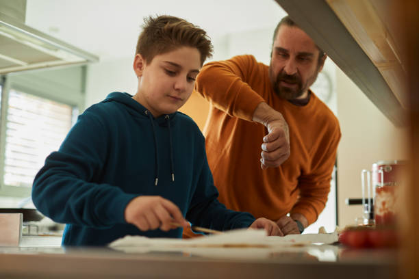 Father and son making a pizza together.