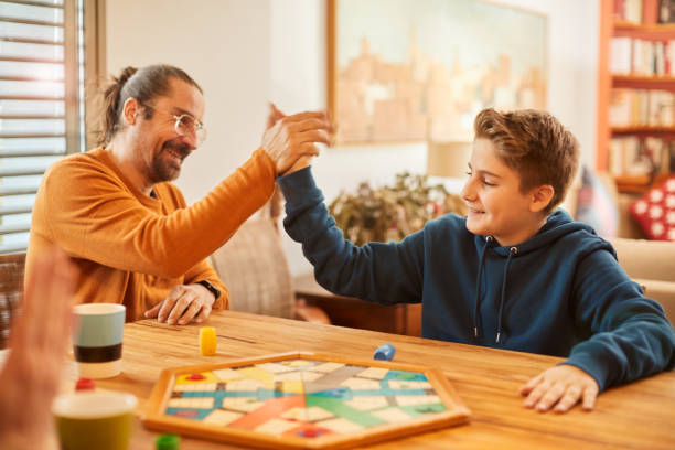 istock Father and son celebrate their victory on a board game hand. 1297737393