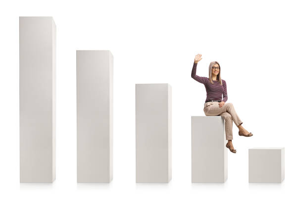 istock Young blond woman with glasses sitting on a white column chart and waving 1297737715