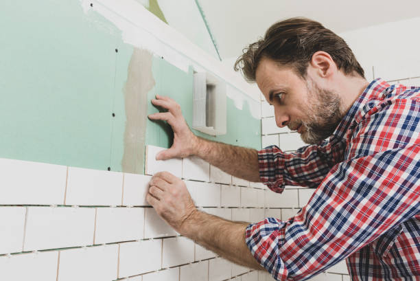 istock Renovation works - interior finishing worker (tiler) laying ceramic tiles on the wall 1297739218