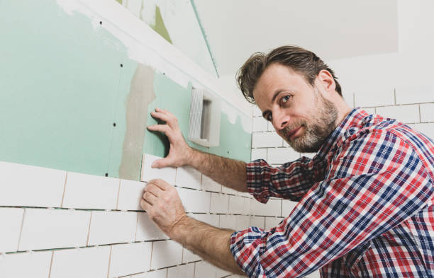 istock Renovation works - interior finishing worker (tiler) laying ceramic tiles on the wall 1297739225