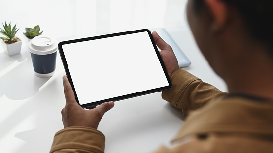 Close up view of young man Hans holding digital tablet with white screen. Blank screen for your advertising text.
