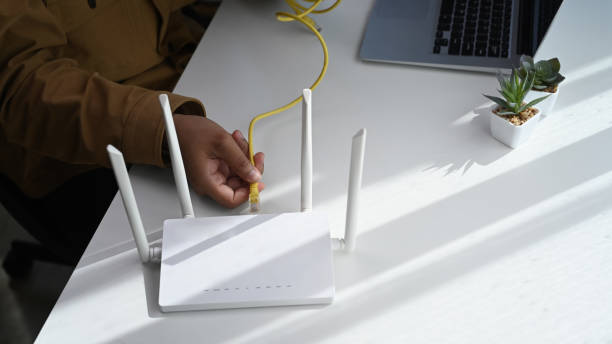 istock Close up view of man plugging in cable to wireless router. Wireless internet concept. 1297740951