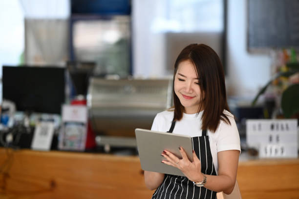 istock Young female entrepreneur in an apron using a digital tablet in her coffee shop. 1297741109