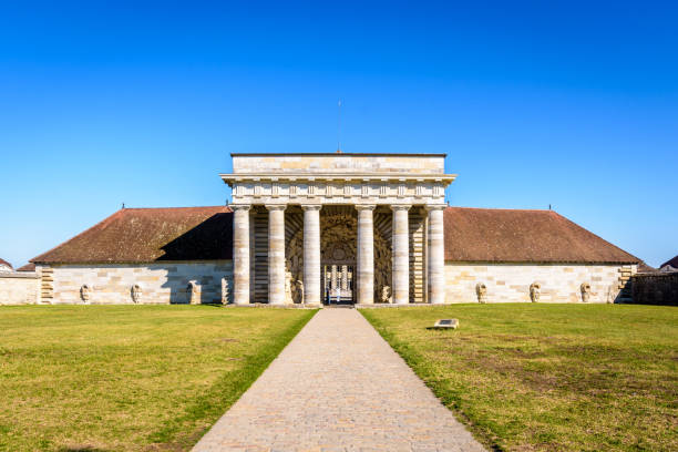 Entrance of the Royal Saltworks in Arc-et-Senans, France. Arc-et-Senans, France - September 1, 2020: Front view of the southern facade of the former Guards building of the Royal Saltworks, with a neoclassical portico, only entrance to the site. doubs photos stock pictures, royalty-free photos & images