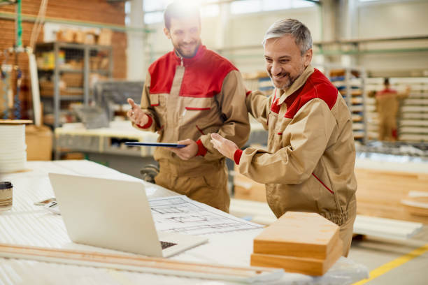 istock Happy carpenters having video call over laptop while working at workshop. 1297742804