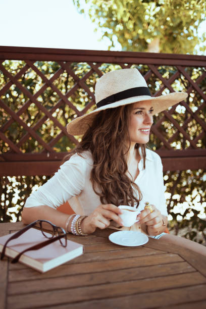 istock relaxed female in shirt sitting at table drinking coffee 1297742879