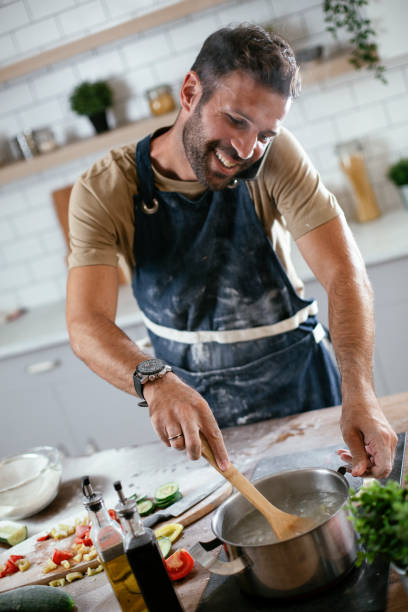 istock Handsome man talking to the phone while cooking 1297743498