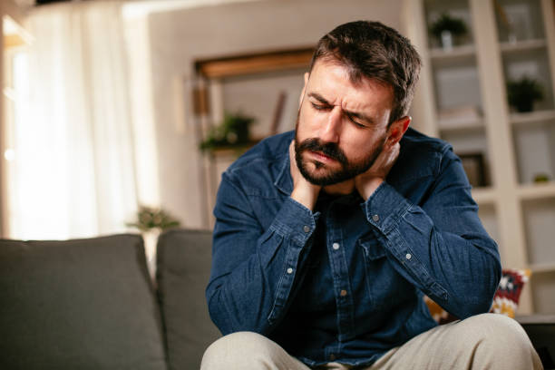 istock Young man sitting on sofa having fever 1297745326
