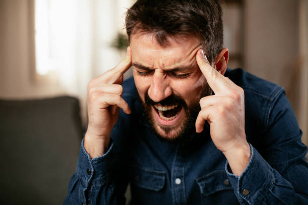 istock Young man sitting on sofa having fever 1297745372