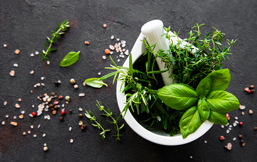 Bunch of aromatic herbs in mortar on a black concrete background