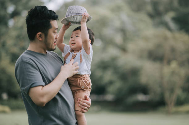 istock asian chinese father carrying his son at public park during weekend bonding playing with hat 1297752512