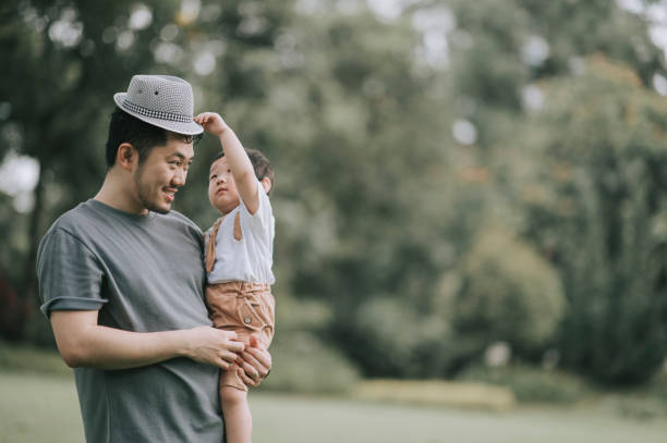 istock asian chinese father carrying his son at public park during weekend bonding playing with hat 1297752628