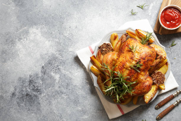 baked whole chicken with rosemary, garlic and ketchup on gray concrete background. roasted chicken stock photo