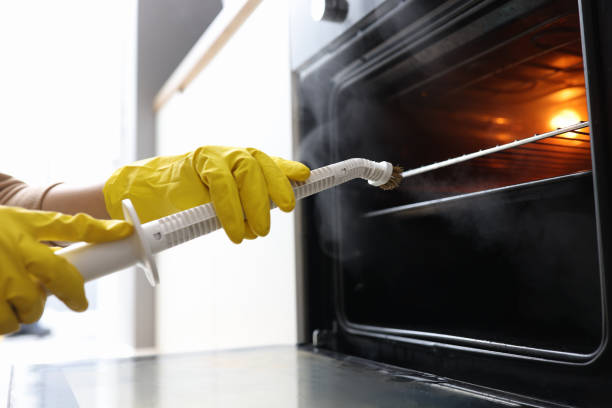 istock Hands in rubber gloves washing oven with steamer concept 1297762171