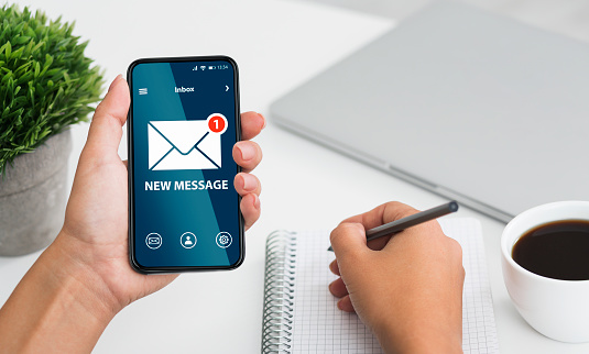 Newslettering Concept. Woman Got New Message On Smartphone While Working In Office, Holding Cellphone With Envelope Icon On Screen, Creative Collage For Email Coomunication And Digital Marketing