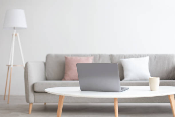 istock Modern scandinavian living room interior. Laptop on white table for work with cup 1297763352