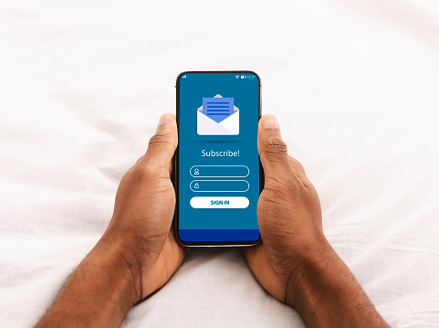 Digital Marketing. Black Man Holding Smartphone With Newsletter Subscription Form And Opened Envelope Icon On Screen While Relaxing In Bed, Creative Collage For Email Communication, Copy Space