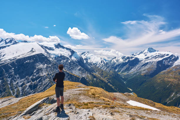 istock Young man standing on a cliff looking over the valley in New Zealand 1297763473