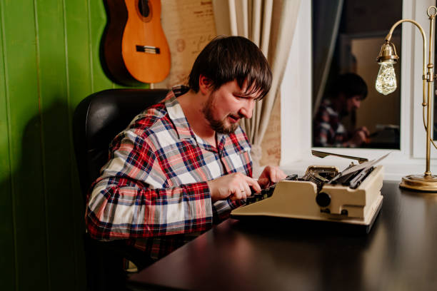 istock a man in plaid pajamas types on a typewriter at night in his home office. 1297763508