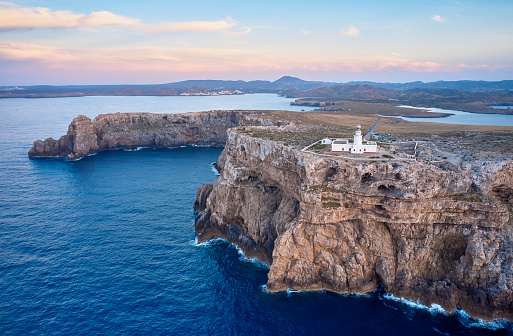 Aerial view of Punta Nati lighthouse in Menorca on top of high cliffs by the sea