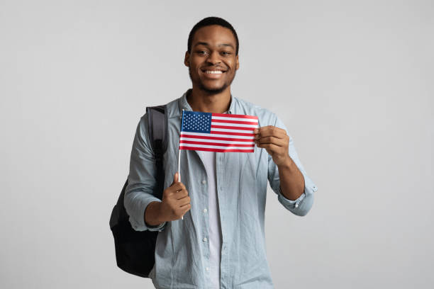istock Positive black guy with backpack holding american flag 1297765832
