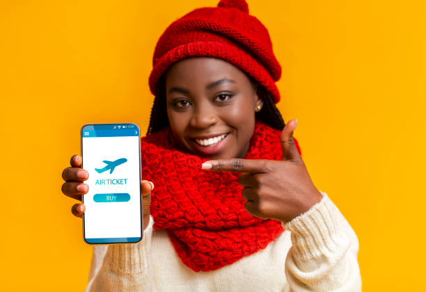 mujer negra alegre apuntando a smartphone con entradas de vuelo aplicación en la pantalla - commercial airplane ticket wildlife reserve travel agency fotografías e imágenes de stock