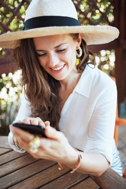 istock happy woman sitting at table sending text message using phone 1297767328
