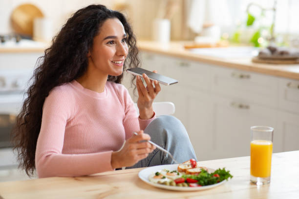 istock Smiling Young Woman With Smartphone Sending Audio Messages While Having Breakfast 1297767486