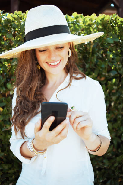 istock smiling stylish woman in shirt using smartphone applications 1297767489