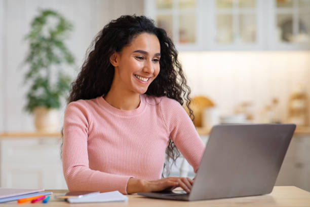 istock Happy beautiful young female freelancer working on laptop in kitchen 1297767515