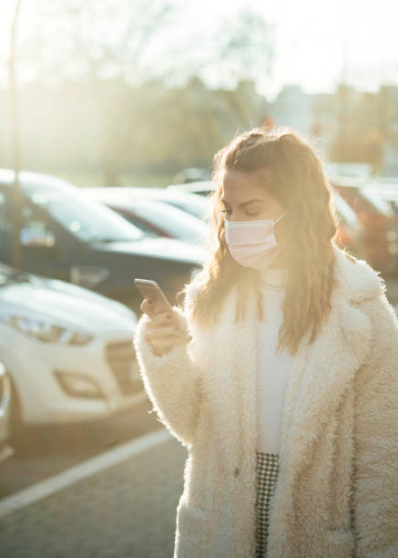 istock Young woman wearing protective face mask and typing text message on mobile phone 1297767576
