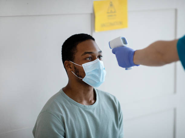 istock Black man having his temperature measured by infrared thermometer at clinic before getting covid-19 vaccine injection 1297768817