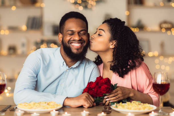 jeune femme noire embrassant ses fleurs de fixation d’homme - anniversary couple rose black photos et images de collection