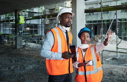 Shot of a young man and woman having a discussion while working at a construction site