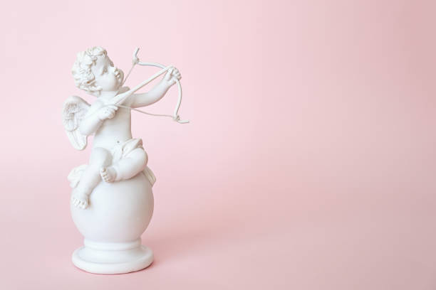 фигурка ангела амура с луком на розовом фоне. день святого валентина - cupid стоковые фото и изображения
