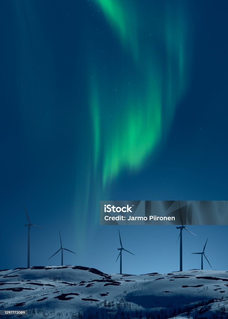 Wind mills at night with aurora borealis on the sky Northern light above wind turbines on snowy hill in winter night Renewable Energy Stock Photo