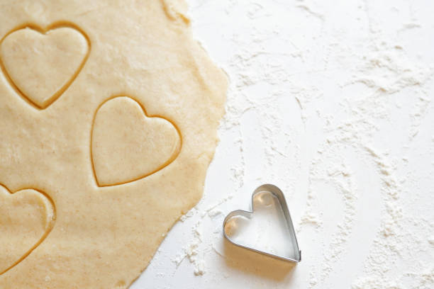 istock Hands pressing heart shaped cookie cutter into dough 1297772380