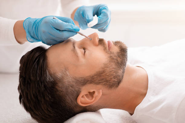 istock Man resting with closed eyes while beautician removing black heads 1297773376